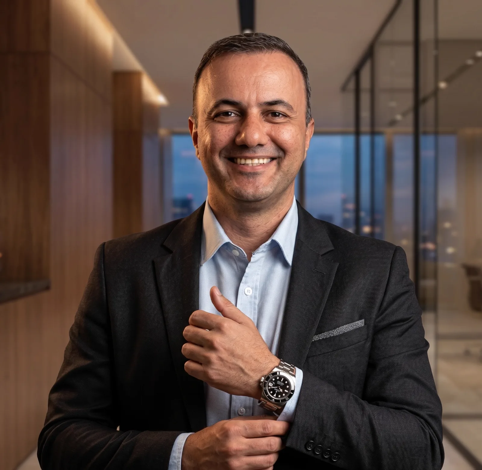 Leonardo Gutiérrez sorrindo, de blazer escuro e camisa clara, em ambiente corporativo.